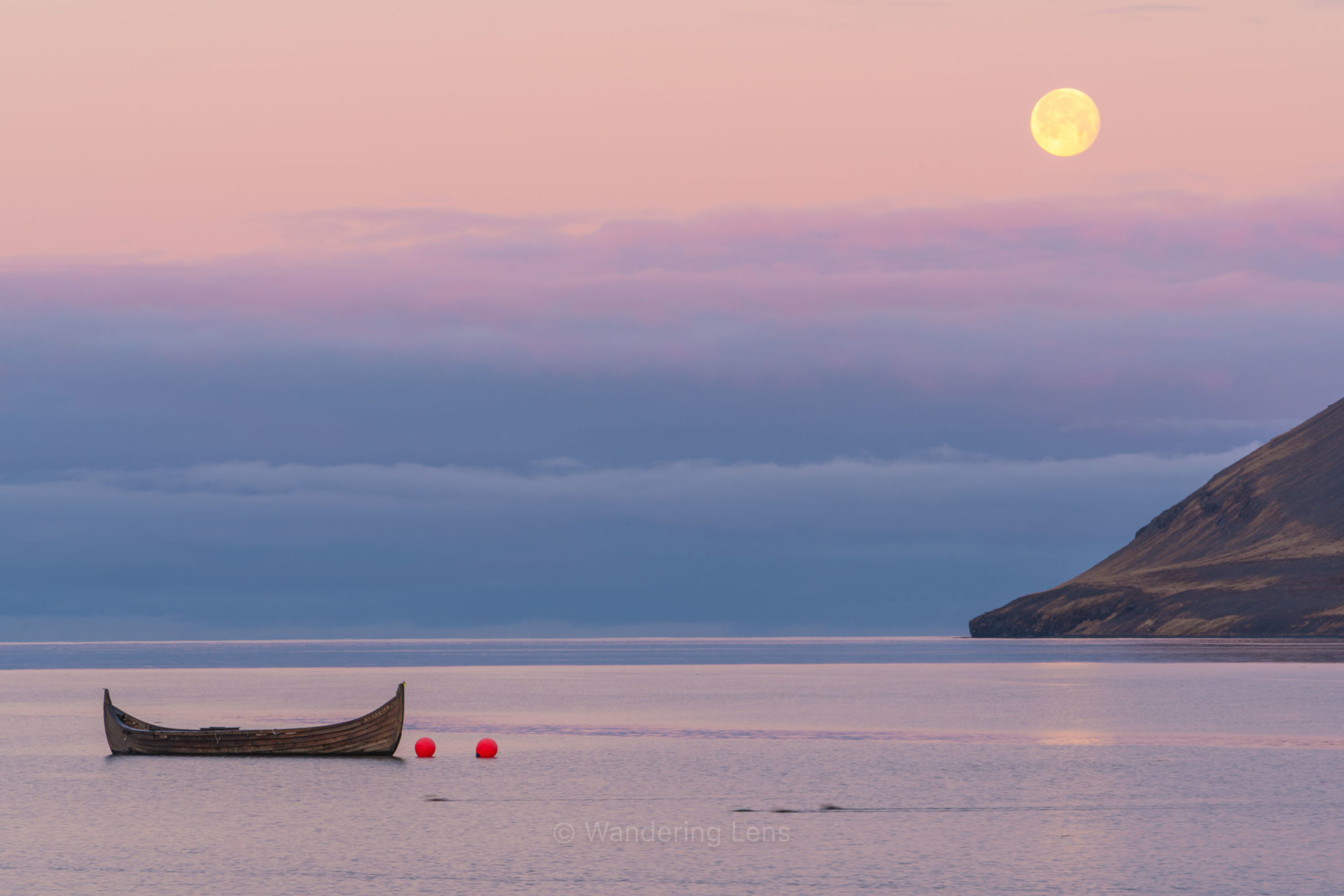A fishing canoe waits under the setting moon